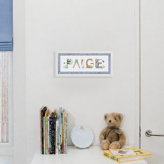 Custom Animal Name Print by The Letter Nest spelling "Paige" in animal letters shown in a nursery in a white frame with a blue gingham border