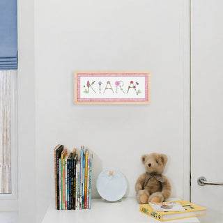 Flower Custom Name Print spelling "Kiara" in flower letters by The Letter Nest in a natural frame with pink gingham border