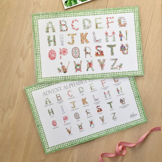 Flat Lay styled photo of The Letter Nest's Advent Alphabet Placemats shown with green border with letters on one side and the key on the verso