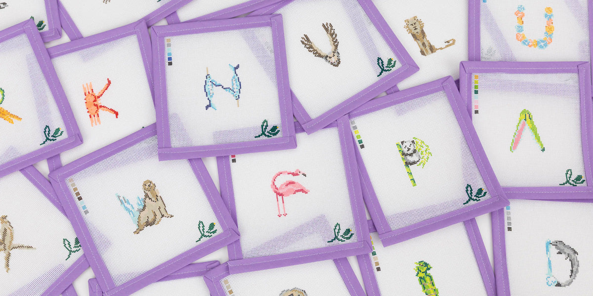 Flatlay image of The Letter Nest x Lycette Needlepoint's canvases featuring Animal letters painted by Sally King McBride
