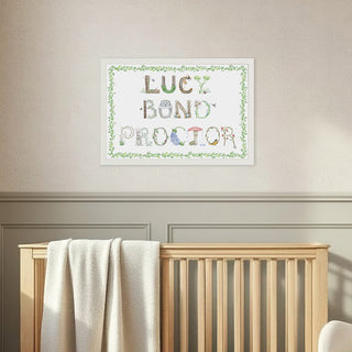 Nursery room with wooden crib, rocking chair, and framed Full Name Print by The Letter Nest in Woodland themed letters with a vine border in a white frame