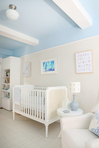 Light blue nursery with a white crib and framed alphabet prints by The Letter Nest