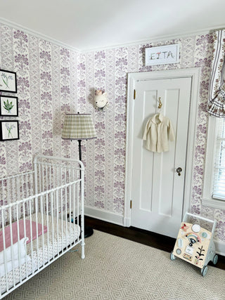 Lavender wallpapered nursery with a white crib and a custom name print reading Etta by The Letter Nest