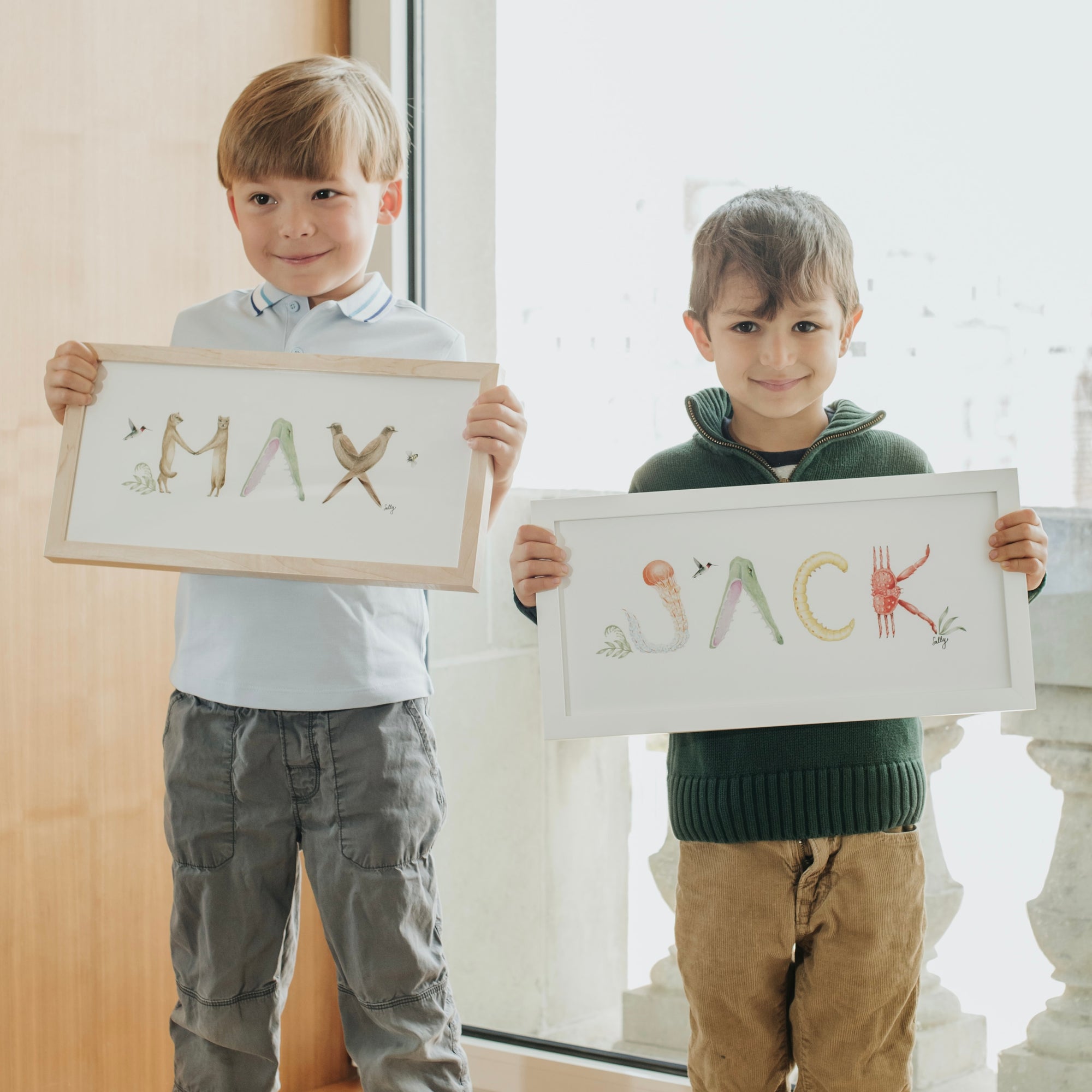 Max and Jack hold their custom Animal Name Prints in natural and white frames